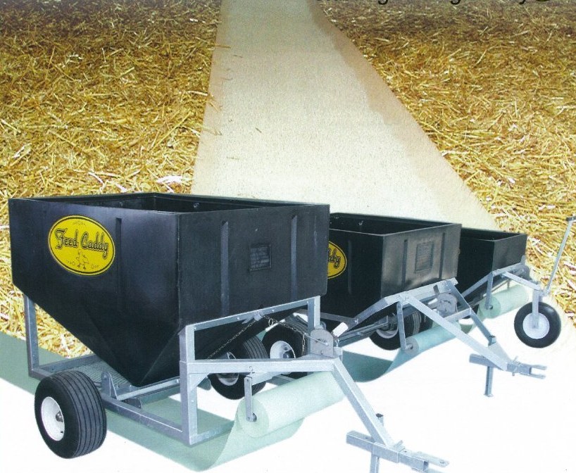 Three Feed Caddy units in a poultry barn with brood paper laid down the centre of the litter